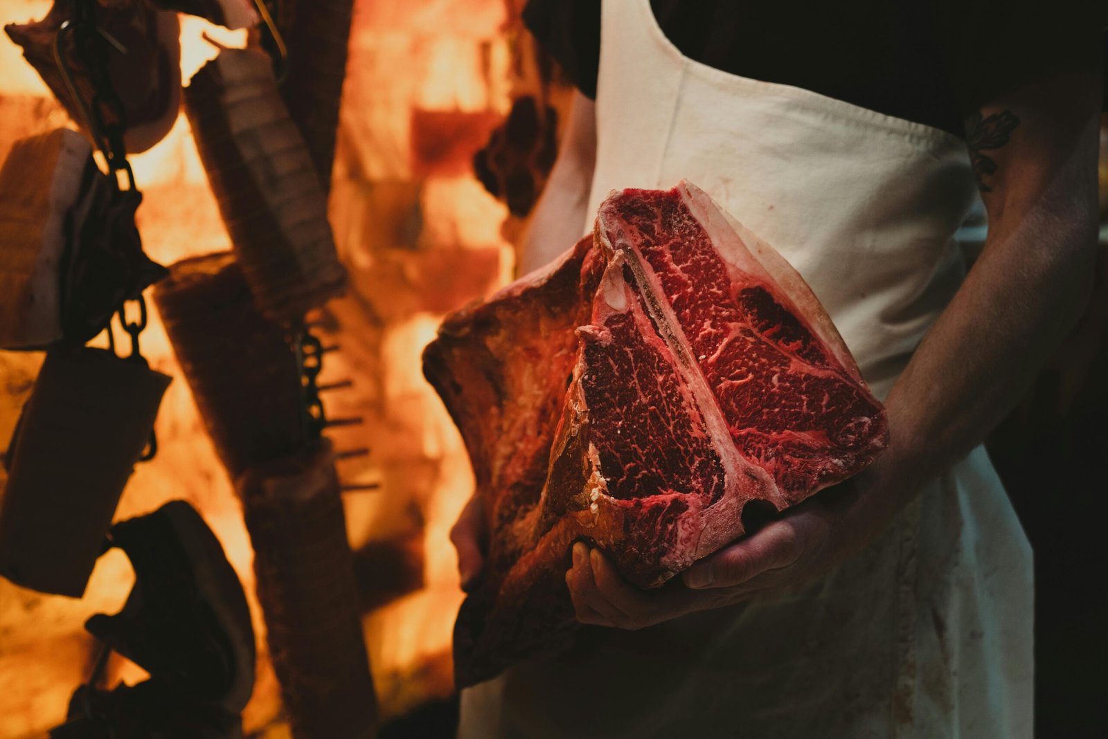 Close-up of a butcher holding a raw T-bone steak in a cold storage area. Perfect for food-related content.